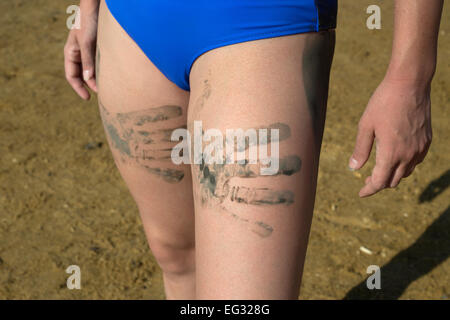 Junge Frau mit Schlamm Palm druckt auf ihre Beine Modell veröffentlicht Stockfoto