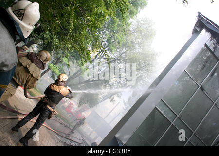 Schwelende Reste eines Ghetto-Hauses mit sprühen Wasser Feuerwehr Feuerwehrmann löschen ein Feuer in einem Mehrfamilienhaus Stockfoto