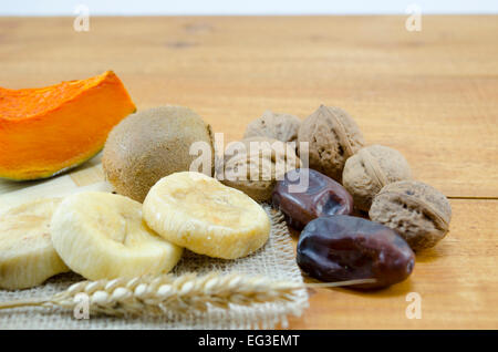 Getrocknete Feigen, Pflaumen, Kürbisse mit Walnüssen und Kiwis auf einem Holztisch Stockfoto