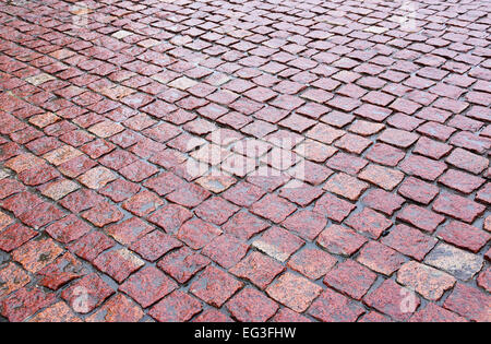 nasses Kopfsteinpflaster aus rotem Granit auf der Straße Stockfoto