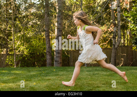 Sieben Jahre altes Mädchen trug ein ärmelloses Kleid, barfuß laufen in ihrem Hinterhof in Issaquah, Washington, USA Stockfoto