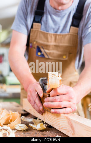 Arbeiten mit Holz Hobel am Werkstück in seiner Werkstatt oder Zimmerei Zimmermann Stockfoto