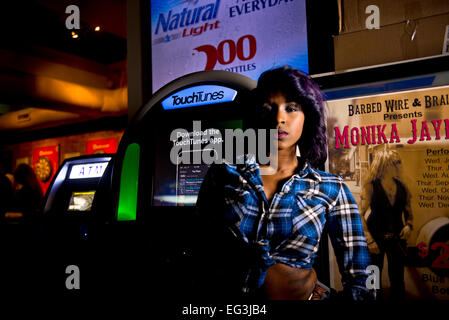 African American Model tatenlos eine Jukebox in einer bar Stockfoto