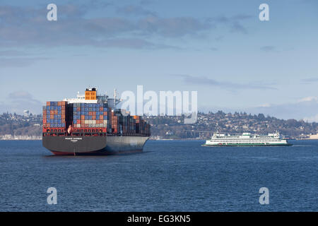 Containerschiff Prag Express verankert in Elliott Bay am Hafen von Seattle am 14. Februar 2015 - Elliott Bay, Seattle, King County, Washington, USA. Die Seattle - Bremerton Fähre überquert in der Nähe. Das Entladen der Fracht wurde während der laufenden Arbeitskampf an der Westküste ausgesetzt. Eigentümer haben einen vier-Tages Shutdown nicht zu zahlen und höhere Prämie Löhne für Wochenend- und Operationen aufgerufen. Union und den Reedern die Hafenarbeiter haben seit neun Monaten in Verhandlungen. Stockfoto