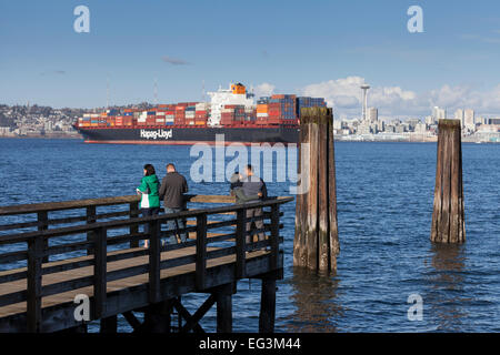 Containerschiff Prag Express verankert in Elliott Bay am Hafen von Seattle am 14. Februar 2015 - Elliott Bay, Seattle, King County, Washington, USA. Zwei Paare im Seacrest Park in West Seattle blicken auf. Das Entladen der Fracht wurde während der laufenden Arbeitskampf an der Westküste ausgesetzt. Eigentümer haben einen vier-Tages Shutdown nicht zu zahlen und höhere Prämie Löhne für Wochenend- und Operationen aufgerufen. Union und den Reedern die Hafenarbeiter haben seit neun Monaten in Verhandlungen. Stockfoto