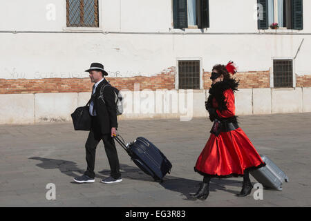 Paar mit Wheelie Koffer oder Trolley Koffer während des Karnevals in Venedig, Veneto, Italien Stockfoto