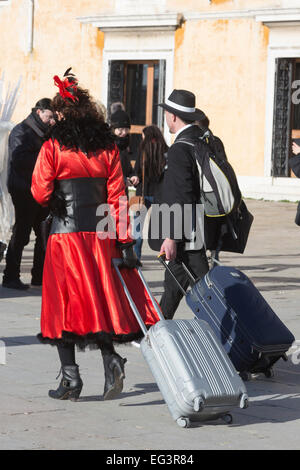 Paar mit Wheelie Koffer oder Trolley Koffer während des Karnevals in Venedig, Veneto, Italien Stockfoto