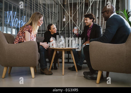 Gemischtrassig Business-Team im Büro sitzen lobby diskutieren neue Geschäftsideen. Junger Mann Trinkwasser. Glückliche junge Menschen du Stockfoto