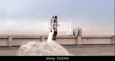 Mann von hinten oben mit Raketenrucksack aufbauend abheben Stockfoto