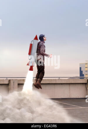 Mann von hinten oben mit Raketenrucksack aufbauend abheben Stockfoto