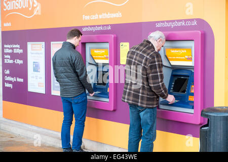 zwei Männer auf die Sainsburys bank Geldautomat ATM in seinen Store Matlock, Derbyshire, England Stockfoto