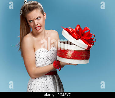 Mädchen ist nicht zufrieden mit ihren gaben vor blauem Hintergrund. Ferien, Urlaub, Feier, Geburtstag-Konzept Stockfoto