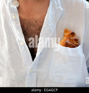 Mann mit offenen Hemd und Brust Haare und Croissant in Hemdtasche Stockfoto