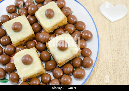 Hausgemachte Desserts in einer Platte mit Schokokugeln und ein weißer Seide Herz auf dem Tisch dekoriert Stockfoto