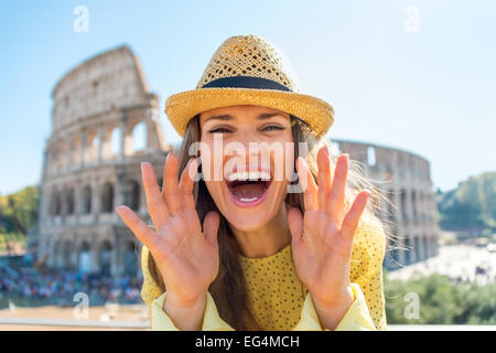 Glückliche junge Frau schreien über Megaphon geformte Hände vor dem Kolosseum in Rom, Italien Stockfoto