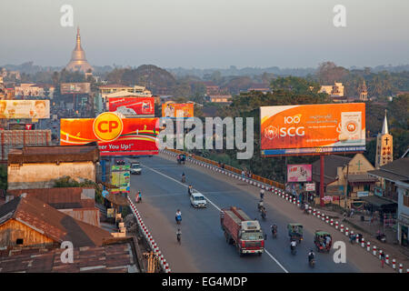 Verkehr in der Straße mit Plakaten in der Stadt Bago, ehemals Pegu, Bago Region, Myanmar / Burma Stockfoto