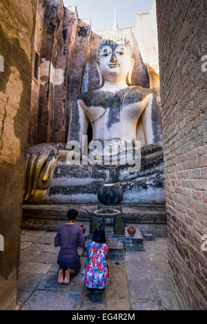 Asien. Thailand, alte Hauptstadt von Siam. Sukhothai archäologischer Park, Wat Si Chum. Paar kniend beten vor Buddha. Stockfoto