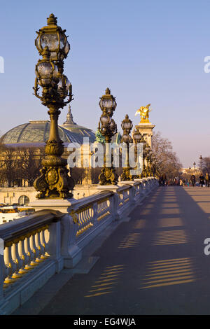 Leuchten am Pont Alexandre III Brücke mit den Kuppeln des Grande Palais hinter. Stockfoto