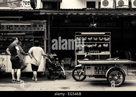 Obst-Stall und Motorrad in der Jalan Alor Hausierer Lebensmittel-Straße in Kuala Lumpur, Malaysia. Schwarz und weiß. Stockfoto