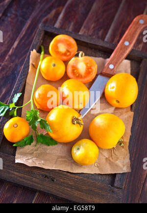 gelbe Tomate in der Holzkiste und auf einem Tisch Stockfoto