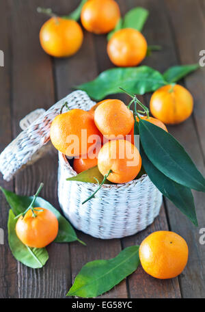 frische Mandarinen in den weißen Korb und auf einem Tisch Stockfoto