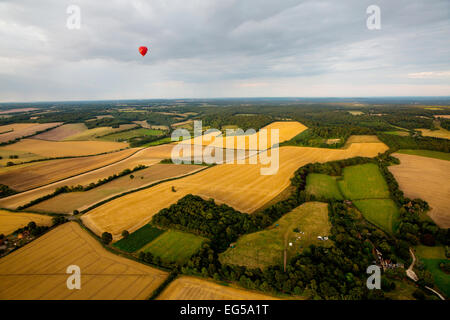 Fernsicht auf roten Heißluftballon über ländliche Landschaft fliegen, South Oxfordshire, England Stockfoto