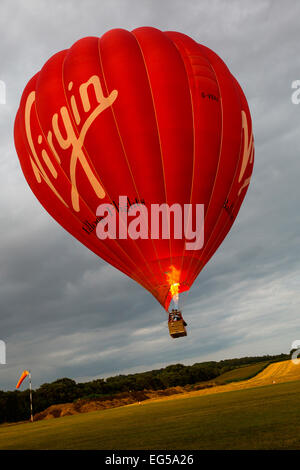 Heißluftballon schweben über Feld mittels Gasbrenner, South Oxfordshire, England Stockfoto