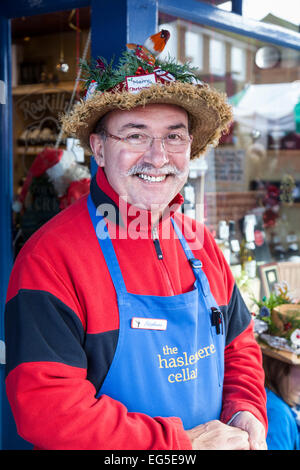 Lebensmittel Verkäufer trägt einen Strohhut dekoriert für Weihnachten in Haslemere Weihnachtsmarkt. Stockfoto