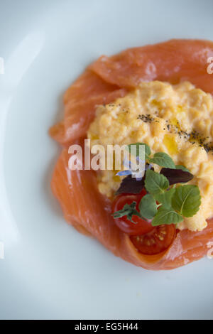 Geräucherter Lachs, Rührei und einer Kirschtomate garnieren. Stockfoto