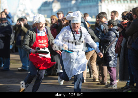 Westminster, London, UK. 17. Februar 2015. Mitglieder des Parlaments Stephen Pound MP (Ealing North) führt parlamentarische Pressekorps Sam Macrory (BBC) in die jährliche Faschingsdienstag parlamentarischen Pancake Race auf Victoria Tower Gardens in Westminster, London, UK-Credit: Jeff Gilbert/Alamy Live News Stockfoto