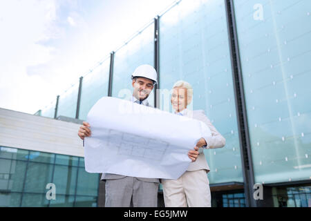 Lächelnde Geschäftsleute mit Bauplan und Helme Stockfoto