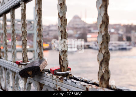 ISTANBUL, Türkei – Love Loses zieren das Geländer der zweistöckigen Galata-Brücke, die das Goldene Horn überspannt, mit der historischen Suleymaniye-Moschee im Hintergrund. Die Brücke, die Eminonu mit Karakoy verbindet, beherbergt sowohl Fahrzeuge als auch Straßenbahnen auf der oberen Ebene, während sich darunter Restaurants befinden. Diese moderne Tradition, Vorhängeschlösser als Symbole der Liebe anzubringen, hat sich auf Brücken weltweit ausgebreitet. Stockfoto