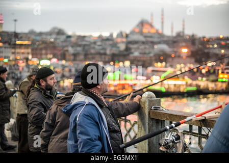 ISTANBUL, Türkei – Fischer säumen das Geländer der historischen Galata-Brücke und werfen ihre Linien in das Goldene Horn hinein. Die zweistöckige Brücke, die Eminonu mit Karakoy verbindet, bietet Platz für Fahrzeuge, Straßenbahnen und Fußgänger auf dem oberen Deck, während sich Restaurants auf der unteren Ebene befinden. Die markante Silhouette der Suleymaniye-Moschee aus dem 16. Jahrhundert dominiert die Skyline über der Brücke. Stockfoto