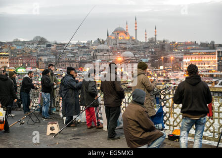 ISTANBUL, Türkei – Fischer säumen das Geländer der historischen Galata-Brücke und werfen ihre Linien in das Goldene Horn hinein. Die zweistöckige Brücke, die Eminonu mit Karakoy verbindet, bietet Platz für Fahrzeuge, Straßenbahnen und Fußgänger auf dem oberen Deck, während sich Restaurants auf der unteren Ebene befinden. Die markante Silhouette der Suleymaniye-Moschee aus dem 16. Jahrhundert dominiert die Skyline über der Brücke. Stockfoto