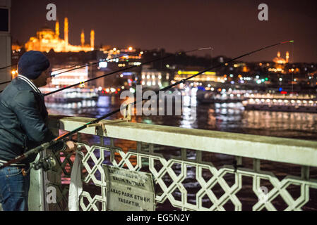 ISTANBUL, Türkei – Fischer säumen das Geländer der historischen Galata-Brücke und werfen ihre Linien in das Goldene Horn hinein. Die zweistöckige Brücke, die Eminonu mit Karakoy verbindet, bietet Platz für Fahrzeuge, Straßenbahnen und Fußgänger auf dem oberen Deck, während sich Restaurants auf der unteren Ebene befinden. Die markante Silhouette der Suleymaniye-Moschee aus dem 16. Jahrhundert dominiert die Skyline über der Brücke. Stockfoto