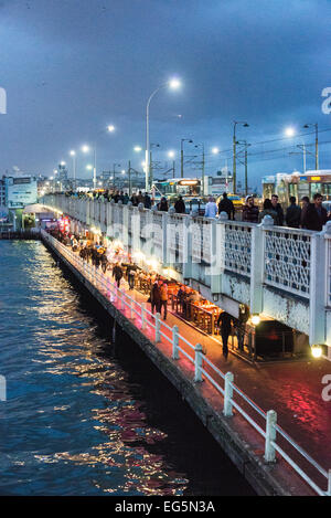 ISTANBUL, Türkei – die zweistöckige Galata-Brücke überspannt in der Abenddämmerung das Goldene Horn, deren charakteristisches zweistufiges Design im Abendlicht beleuchtet wird. Auf dem oberen Deck der Brücke befinden sich Fahrzeuge und Fußgänger, während im unteren Stockwerk Restaurants und Cafés untergebracht sind. Das 490 Meter hohe Gebäude dient sowohl als wichtige Verkehrsanbindung als auch als beliebtes abendliches Ziel. Stockfoto