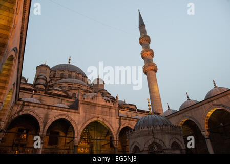 Neue Moschee Yeni Cami 17. Jahrhundert Osmanische Architektur Istanbul Türkei | ISTANBUL — Ein einzelner beleuchteter Minarett erhebt sich vor dem dunkler werdenden Himmel neben der gewölbten Silhouette der Yeni Cami, der Neuen Moschee, im Istanbuler Viertel Eminönü. In zwei Phasen erbaut, die durch etwa sechzig Jahre getrennt sind und 1663 abgeschlossen wurden, beherbergt die Moschee eine zentrale Kuppel mit einem Durchmesser von 57 Fuß (17,5 m) und Innenwände, die mit İznik-Fliesen verkleidet sind, was den Höhepunkt des klassischen osmanischen Kaiserstils markiert. Stockfoto