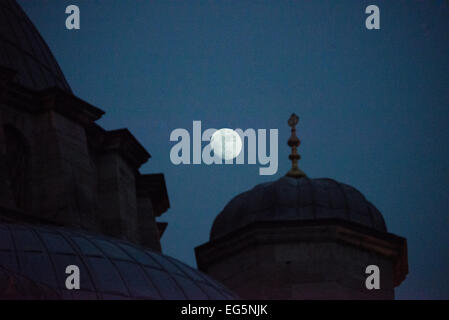 Neue Moschee Silhouette Mond Istanbul Türkei // ISTANBUL, Türkei — die Silhouette der Neuen Moschee (Yeni Camii) erscheint am Nachthimmel gegen den Mond. Im Stadtteil Eminönü am südlichen Ende der Galatebrücke gelegen, wurde die neue Moschee 1663 nach einer verlängerten Bauzeit, die 1597 begann, fertiggestellt. Ursprünglich von Valide Sultan Safiye Sultan in Auftrag gegeben und später unter Valide Sultan Turhan Hatice Sultan fertiggestellt, stellt die Moschee das letzte Beispiel der klassischen osmanischen kaiserlichen Moschee-Architektur dar. Der große Gebetssaal der Moschee zeigt das charakteristische osmanische Kaiserhaus Stockfoto