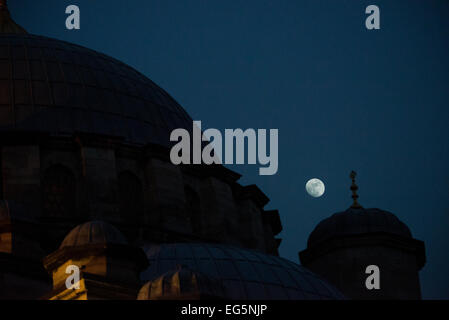 ISTANBUL, Türkei / Türkiye – Eine Silhouette eines Teils des Daches der Neuen Moschee vor dem Mond am Nachthimmel. Die neue Moschee (oder Yeni Cami) liegt im geschäftigen Viertel von Istanbul, am südlichen Ende der Galata-Brücke. Sie stammt aus dem Jahr 1665. Der große Gebetssaal ist im charakteristischen osmanischen Kaiserstil dekoriert. Stockfoto