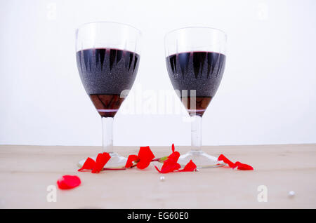 Zwei Kristallgläser Wein auf einem Tisch mit Blütenblättern Stockfoto