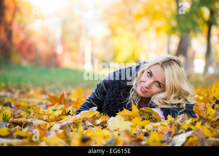 blonde Frau, die im Herbst Park liegt Stockfoto