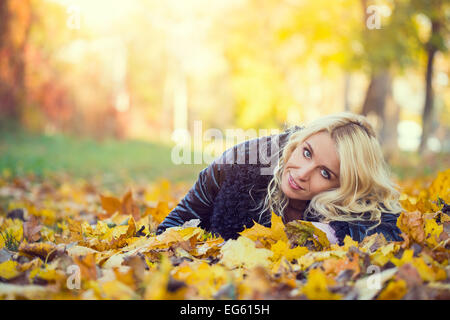 blonde Frau, die im Herbst Park liegt Stockfoto