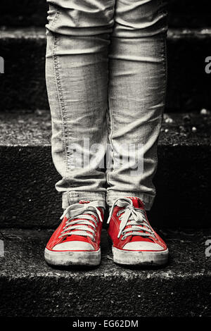 Kleines Mädchen in rote Turnschuhe und Jeans auf der Treppe stehen. Ersten Schritt zu machen. Stockfoto