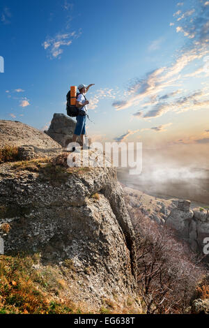 Touristen auf einem hohen Felsen bei Sonnenaufgang Stockfoto