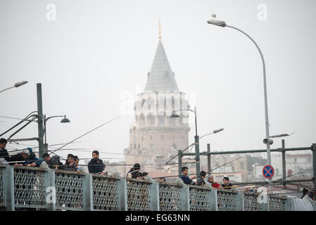 ISTANBUL, Türkei – Fischer säumen die historische Galata-Brücke, die das Goldene Horn überspannt, mit dem mittelalterlichen Galata-Turm, der sich im Hintergrund hervorhebt. Der Turm aus dem 14. Jahrhundert, der von den Genuesen erbaut wurde, ist eines der bekanntesten Wahrzeichen Istanbuls. Die Szene fängt zwei dauerhafte Merkmale der Kultur am Wasser Istanbuls ein. Stockfoto