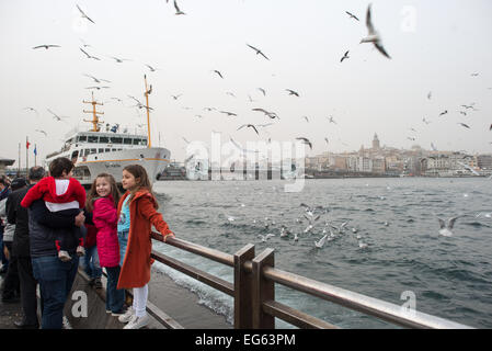 ISTANBUL, Türkei - ISTANBUL, Türkei - zwei kleine Mädchen posieren für Fotos mit den Möwen am Ufer von Eminonu in Istanbul. Im Hintergrund befindet sich der Galataturm. Eminonu ist eine historische Gegend mit einer reichen osmanischen Vergangenheit und das Herz des alten Istanbul, wo Händler und Touristen sich in einem farbenfrohen Spektakel des kulturellen Austauschs vereinen. Stockfoto