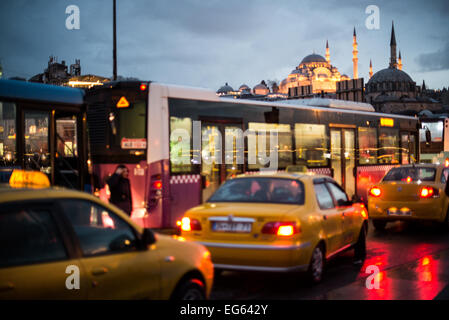 Süleymaniye-Moschee Verkehr Galata-Brücke Istanbul | ISTANBUL, Türkei — Taxis und ein Stadtbus stehen im Stau nahe der Galata-Brücke in Eminonu, während die beleuchtete Süleymaniye-Moschee auf dem Hügel dahinter leuchtet. Die 1557 für Sultan Süleyman den Prächtigen vom Hofarchitekten Mimar Sinan fertiggestellte Moschee bleibt eine prägende Silhouette der Altstadt und überblickt eine Kreuzung, die seit der osmanischen Eroberung 1453 das Verkehrsnetz Istanbuls verankert hat. Stockfoto
