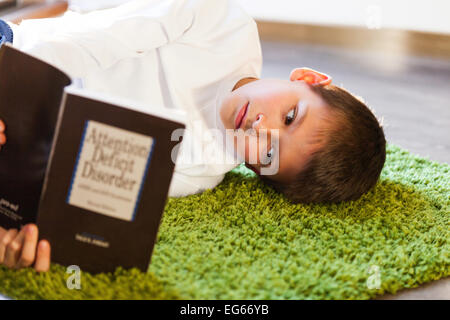 Junge liest ein Buch auf hinzufügen Stockfoto