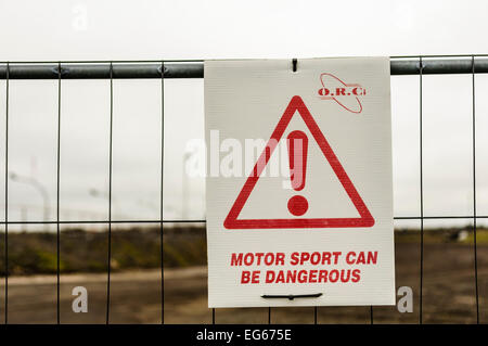 Schild an einer Rennstrecke berät die öffentlichkeit, dass Motorsport gefährlich sein kann. Stockfoto