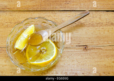Glasplatte gefüllt mit Honig und Zitrone Scheiben und einem Holzlöffel Stockfoto